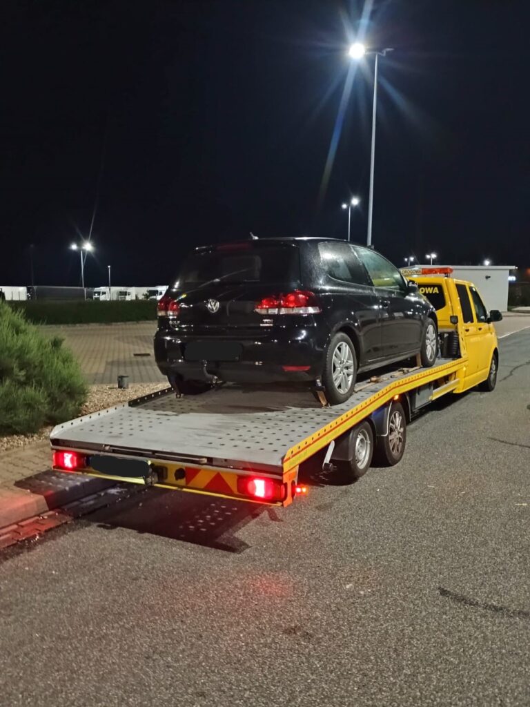 Laweta Świeradów-Zdrój transportująca pojazd na autostradzie, zapewniając bezpieczny przewóz.