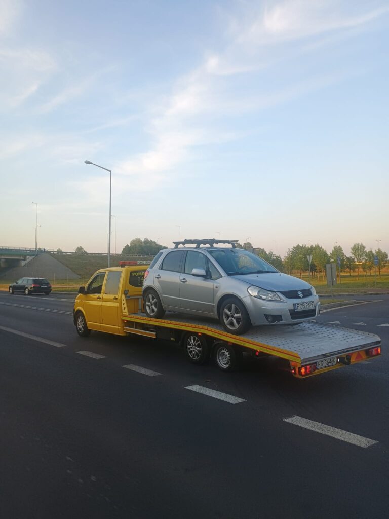 Laweta w Świeradowie-Zdroju przewożąca samochód osobowy na tle górskich krajobrazów.